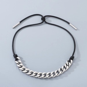 Macro detail of silver stainless steel Cuban chain and adjustable black wax cord necklace