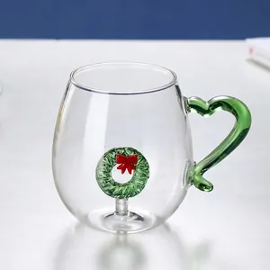 Detail of creative glass mug with green heart handle and 3D Christmas wreath inside