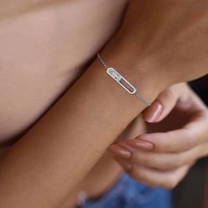 Detailed close-up of a silver minimalist sliding cross bracelet with three zircons