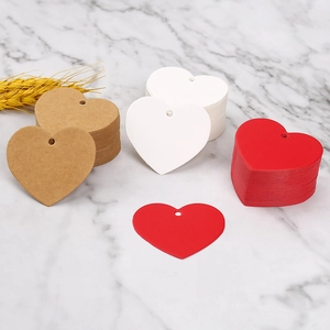Flat lay of heart-shaped paper gift tags in kraft, white, and red on marble background