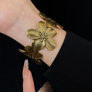 Macro detail of vintage gold cuff bracelet featuring intricate layered metal flower petals