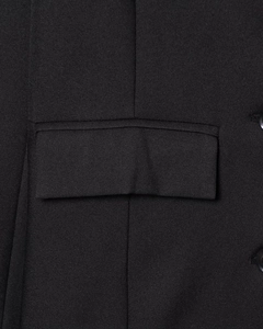 Close-up of black blazer pocket flap showing premium fabric texture and fine stitching
