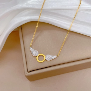 Detail of gold titanium steel wing necklace with diamonds on a satin background