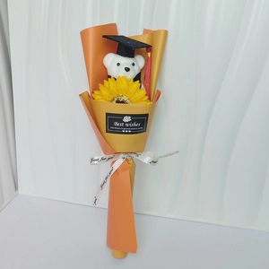 Detail of graduation bear with sunflower bouquet in orange wrap and Best Wishes tag