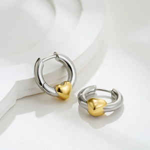 Detail of two-tone hoop earrings with a gold heart element on polished silver metal