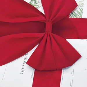 Close-up of large red velvet Christmas bow featuring soft plush texture on white magazine