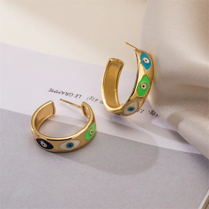Detail of C-shaped gold-plated copper earrings with colorful enamel devil eye patterns