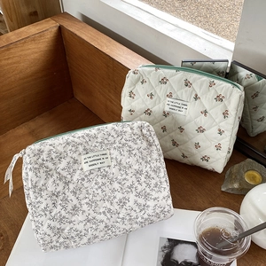 Detail of floral and cherry print quilted cotton makeup bags with green zippers