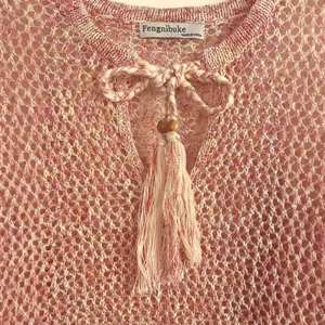Pink orange hollow knit long sleeve top with tassel drawstring and shell accents
