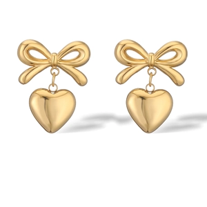 Polished gold bow and heart dangle earrings made of stainless steel on white background