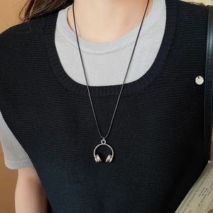 Close-up of a silver headphone pendant necklace with a black cord on a female model
