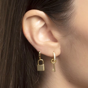 Detail shot of a model wearing asymmetric gold padlock and diamond-encrusted key earrings