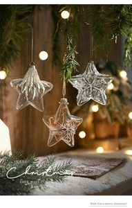 Three clear star-shaped glass ornaments with white sequins and pearls on a festive tree