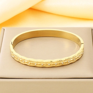 Macro detail of 18K gold plated stainless steel bangle with pavé zircon stones on satin