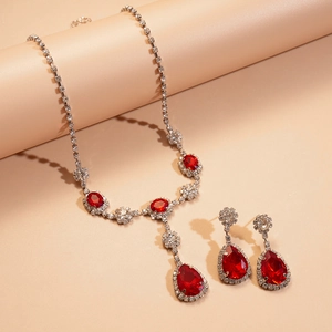 Détail de parure collier et boucles d'oreilles goutte argentées avec strass rouges
