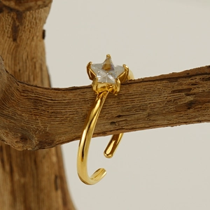Polished 18K gold star zircon open ring displayed on a natural wooden branch background