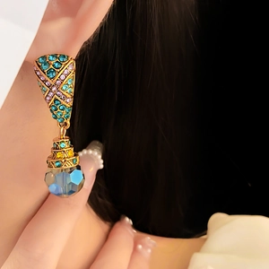 Detail of vintage earrings with blue trapezoid crystals and rhinestones on model ear