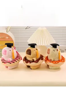 Capybara plush toys with graduation caps and donuts in pink, brown, and yellow colors