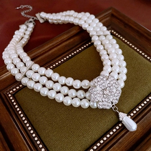 Detail of triple-layer pearl necklace with rhinestone flower and teardrop pendant
