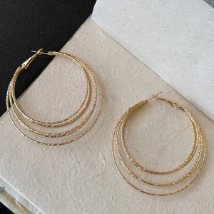 Detail of gold multi-layer geometric hoop earrings with hammered texture and lever back