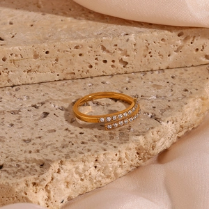 Close-up of gold plated adjustable cross ring with pavé zircons on beige stone