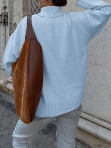 Vista posteriore del maglione a collo alto in maglia azzurra con borsa a tracolla marrone