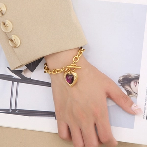 Detail of OT clasp gold chain bracelet with purple heart gemstone on a model's wrist
