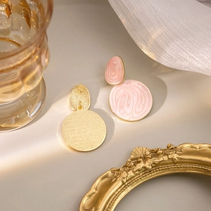 Detailed close-up of pink marble texture enamel earrings with elegant gold metallic edges