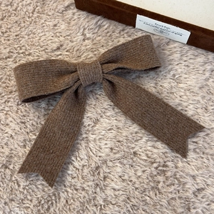 Macro detail of dark brown knitted bow hair clip with textured wool fabric for winter