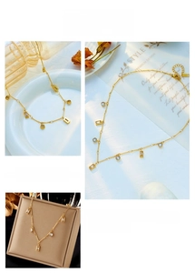Detail of gold chain necklace featuring geometric square and blue crystal round pendants