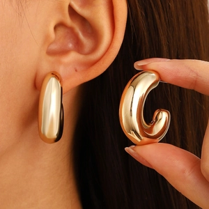 Detailed close-up of chunky gold-plated hollow C-shaped hoop earrings with a mirror finish