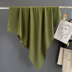 Detail of olive green cotton linen scarf texture hanging on a metal hanger
