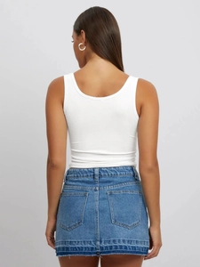 Rear view of white ribbed U-neck sleeveless tank top paired with a denim skirt