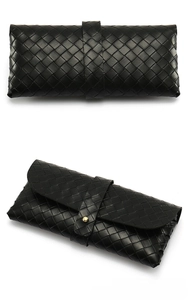Détail macro d'une pochette à lunettes en cuir tressé noir avec fermoir doré chic