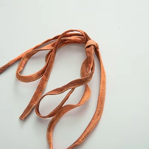 Macro detail of burnt orange velvet fabric texture and soft knotted fringe finish