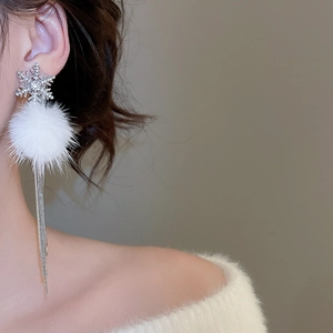 Detail of silver snowflake earrings with white fur balls and long tassels on model