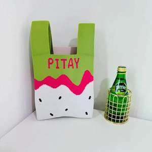 Detail of knit pitaya tote bag showing strawberry colors and green top strap texture
