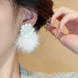 Gros plan sur des boucles d'oreilles fleur élégantes avec pétales blancs et pompons doux