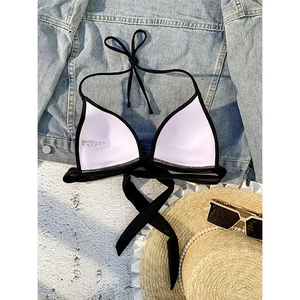 Flat lay of black halter bikini top with straw hat and accessories for beach vacation