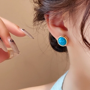 Close-up of vintage round turquoise earrings with gold-plated hollow edges on ear