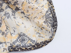 Detail of metallic print fabric with yellow black pattern and fine gold thread stitching
