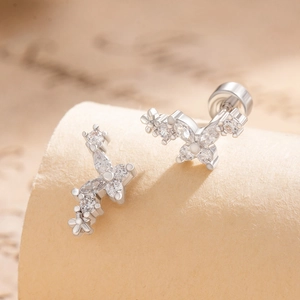 Silver flower and butterfly stud earrings with zircon stones on vintage paper background