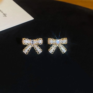 Macro shot of sparkling zircon bow earrings with square cut stone on black velvet