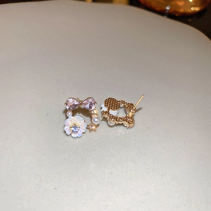 Close-up of pink bow crystal, pearl and white flower earrings on a ceramic dish