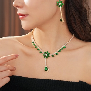 Exquisite gold necklace and earring set featuring green teardrop zircons in floral design