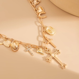 Golden multi-pendant necklace featuring cowboy hat, cross, and heart charms on a sleek surface
