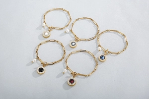 Detail of five gold stainless steel bracelets with colorful crystal pendants and pearls