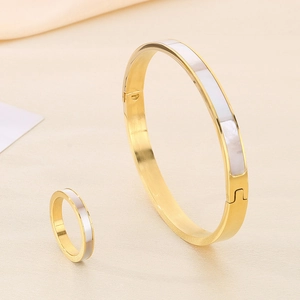 Golden shell inlay ring and bangle set displayed on beige silk texture backdrop