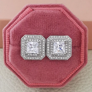 Macro shot of square zircon earrings with halo diamonds in a pink velvet jewelry box