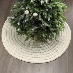Creamy white chunky knit Christmas tree skirt on dark wood floor for holiday home decor